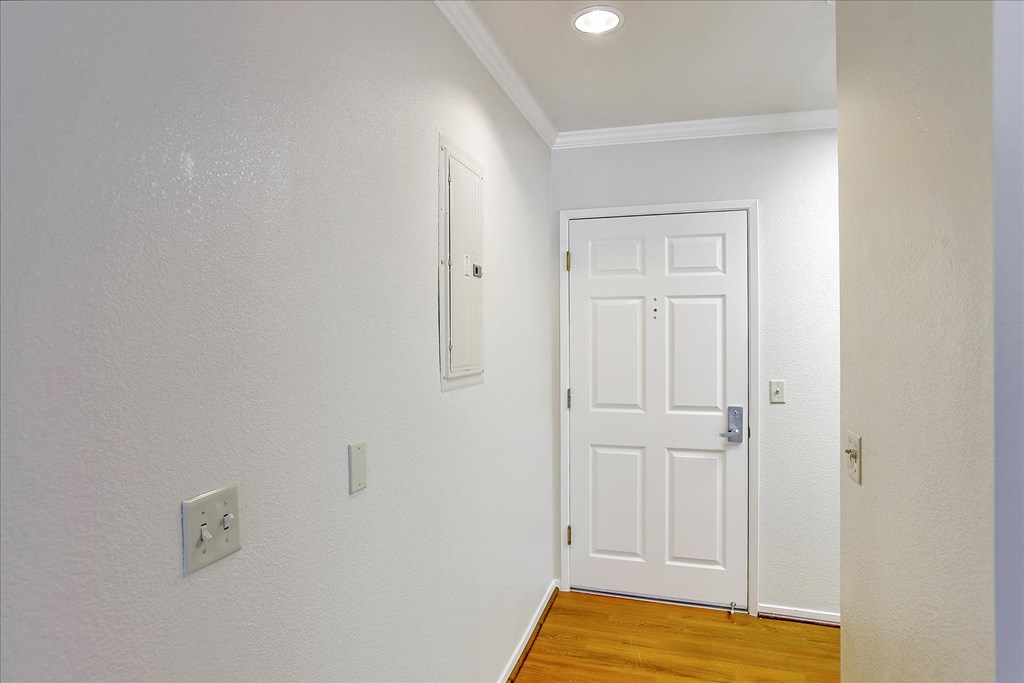 A white door is in a room with a light switch on the wall.