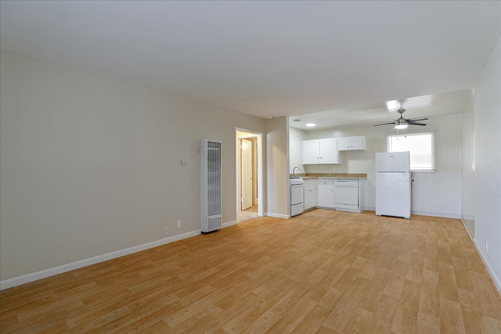 an empty living room and kitchen with a wood floor