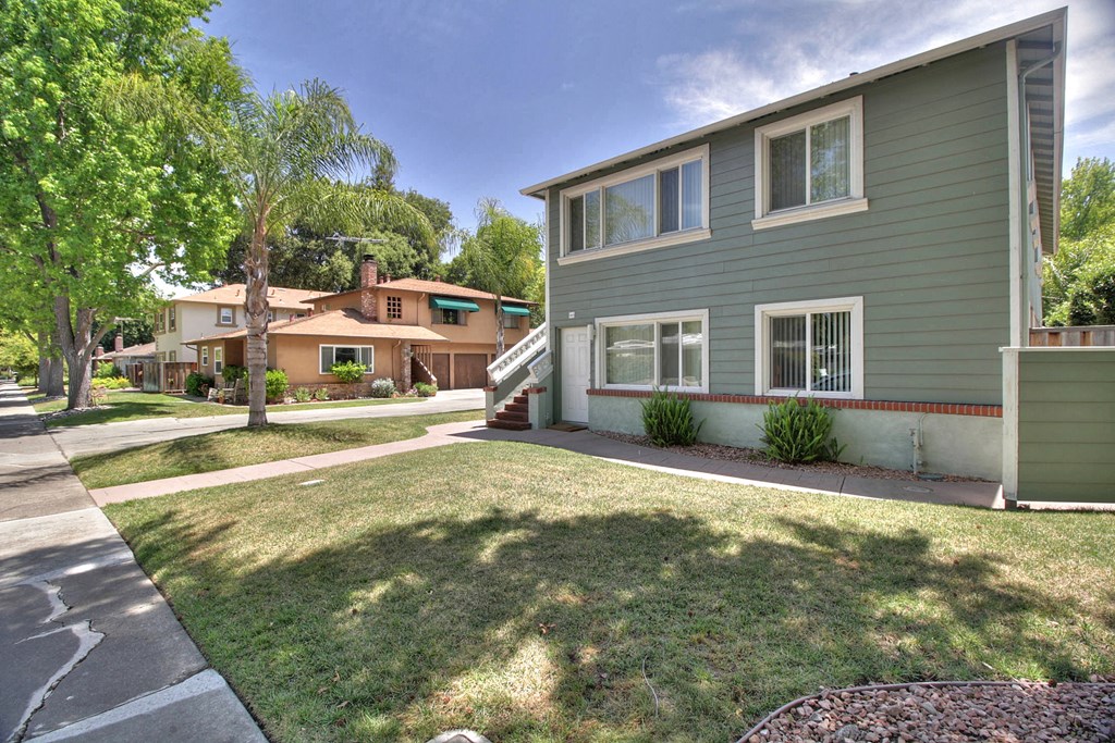 a green house with a yard and a sidewalk