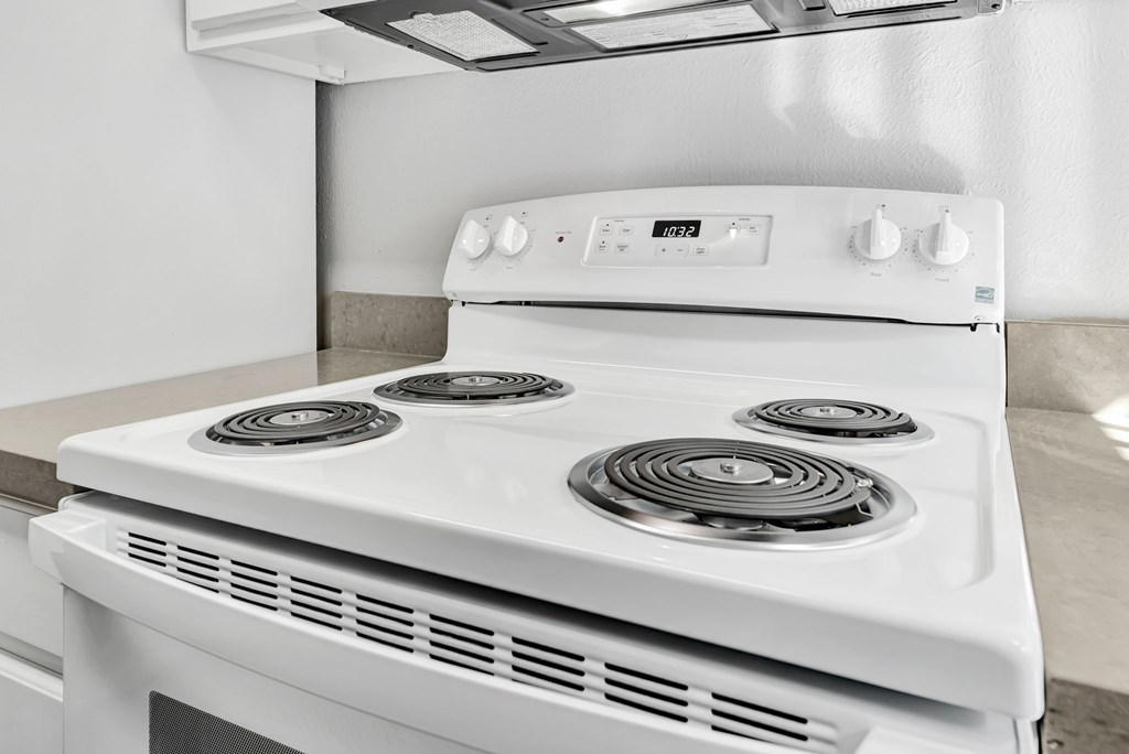 A white gas stove with four burners and a control panel.