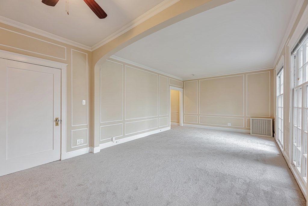 A spacious room with a carpeted floor and a ceiling fan.