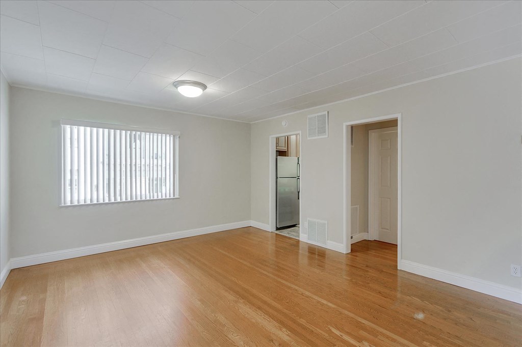 an empty living room with wood flooring and a window