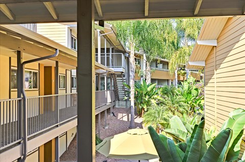 A view of a balcony with a railing and a yellow umbrella.