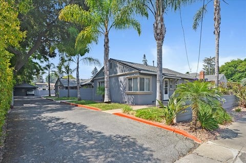 a house with a street and palm trees in front of it