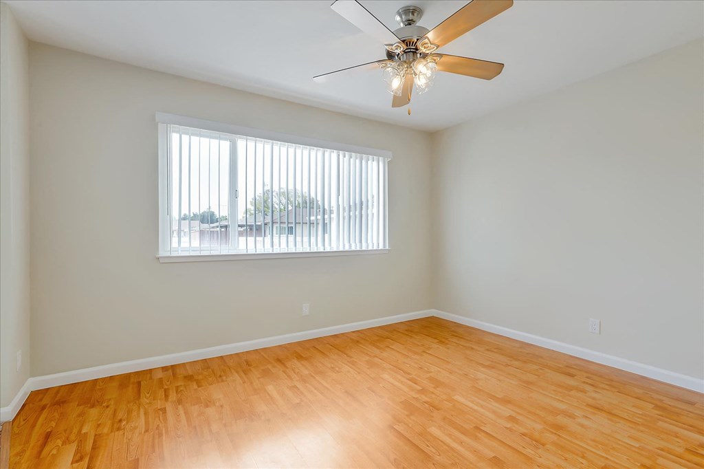 an empty living room with a ceiling fan and a window