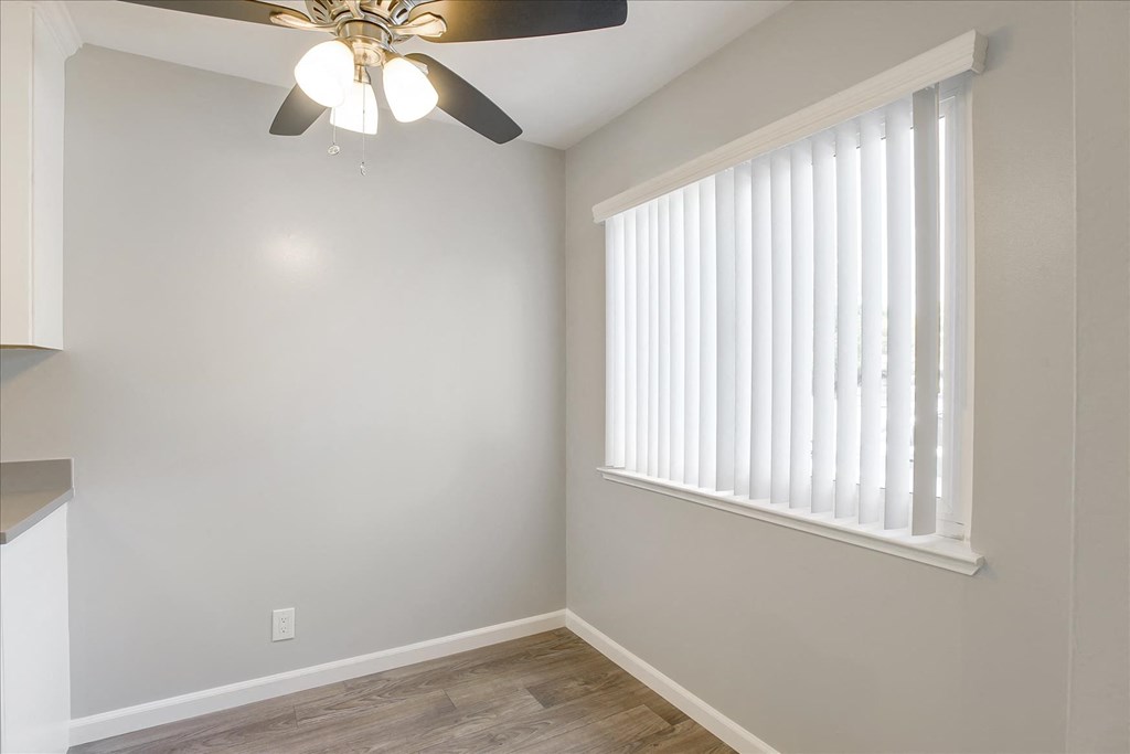A room with a ceiling fan and a window with blinds.