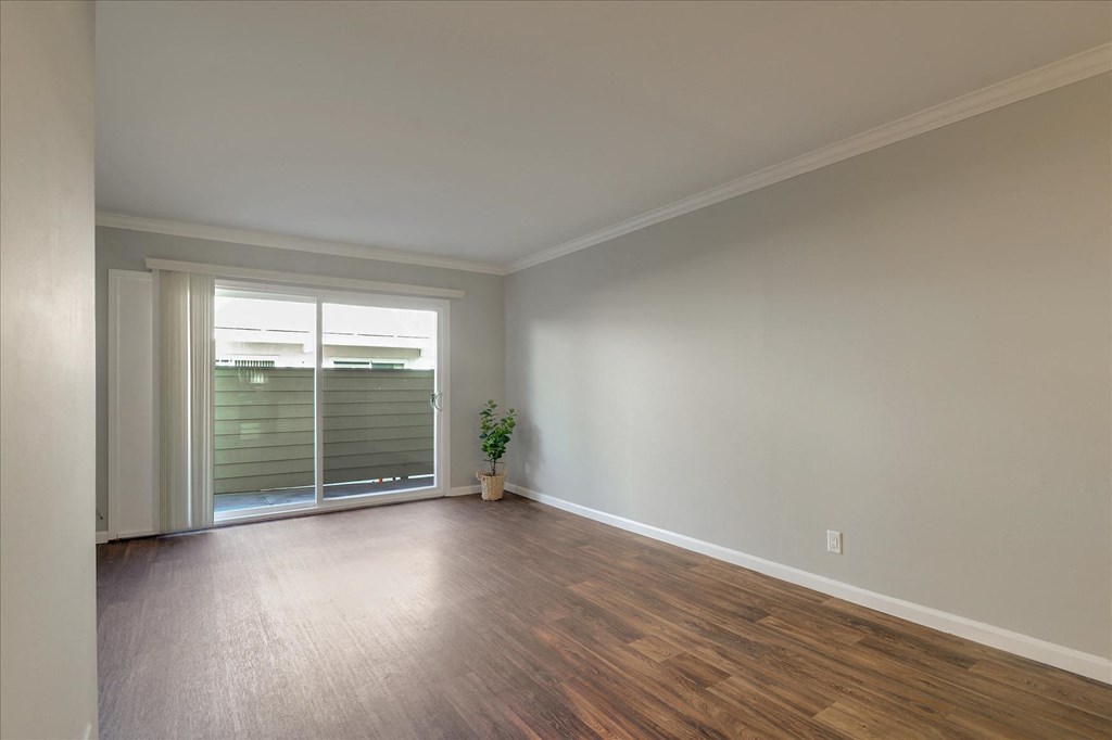an empty living room with a sliding glass door to a patio