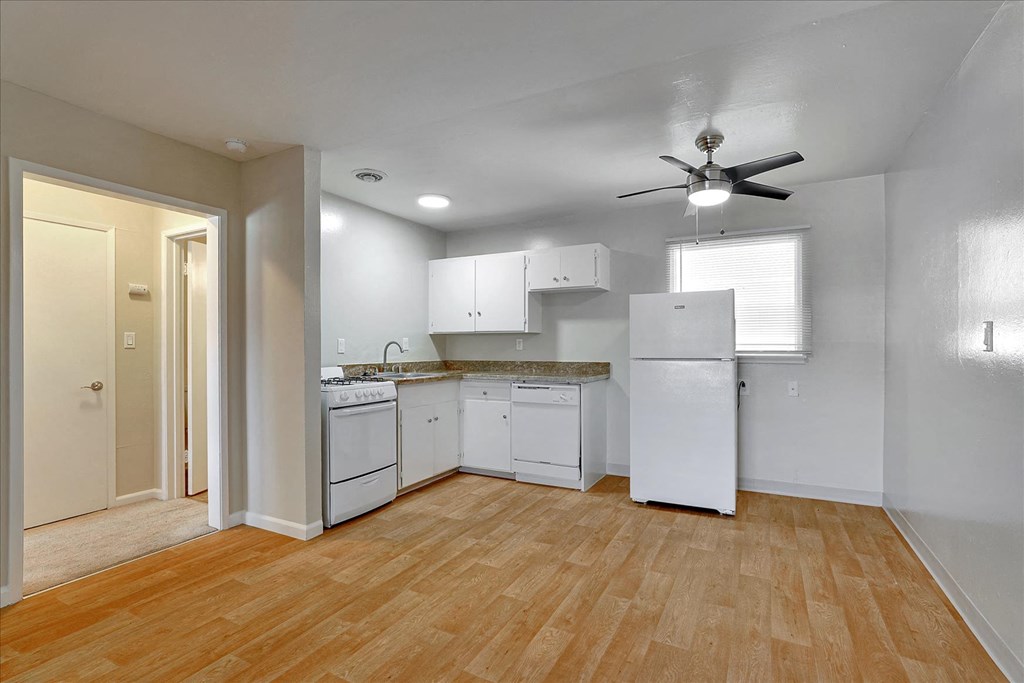 a kitchen with white appliances and a ceiling fan