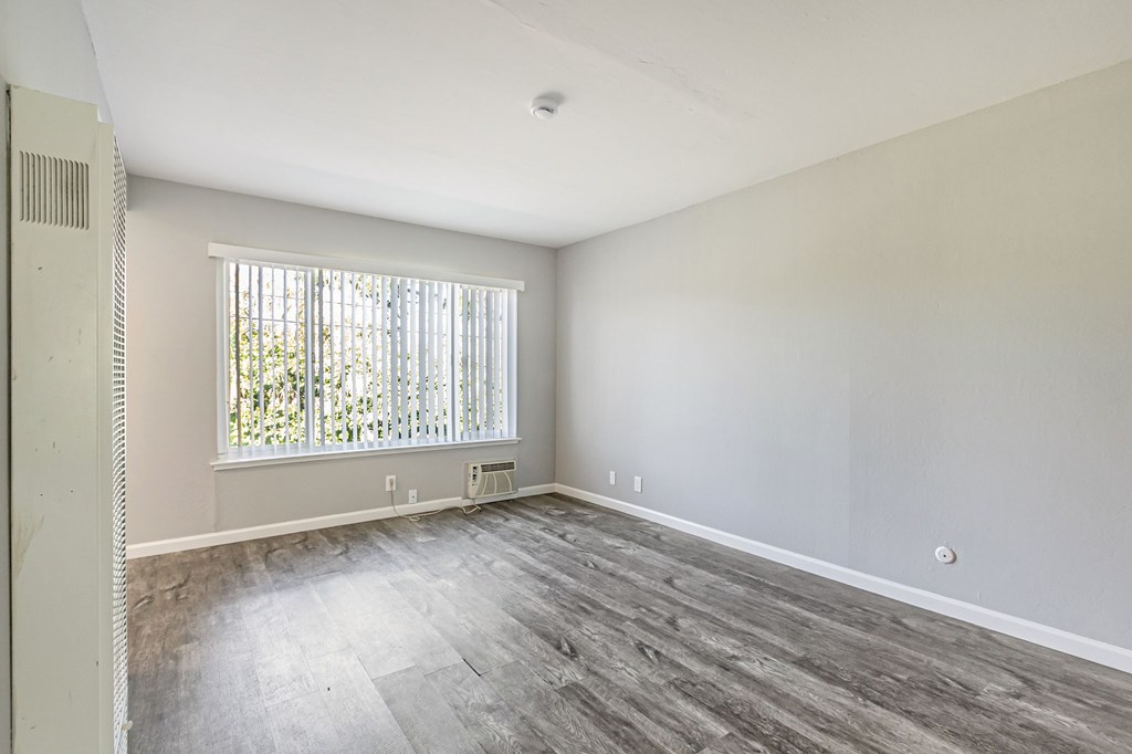 A room with a window and a wooden floor.
