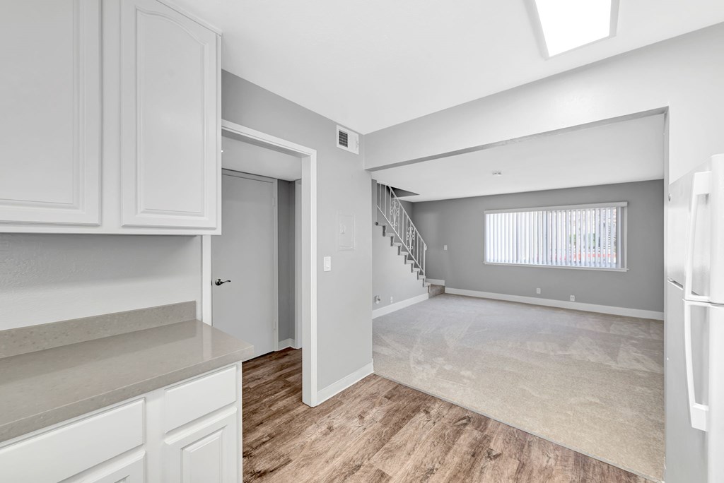 A spacious kitchen with white cabinets and a wooden floor.