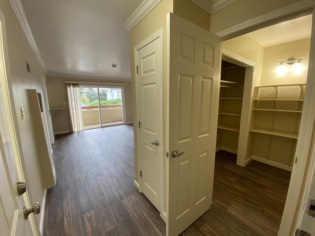 A room with a white door and a window with a view of a street.