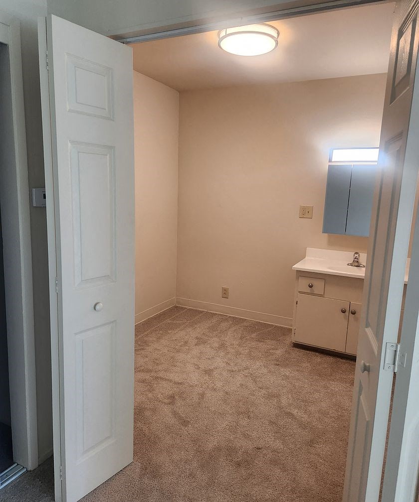 A white door is open to a room with a carpeted floor.