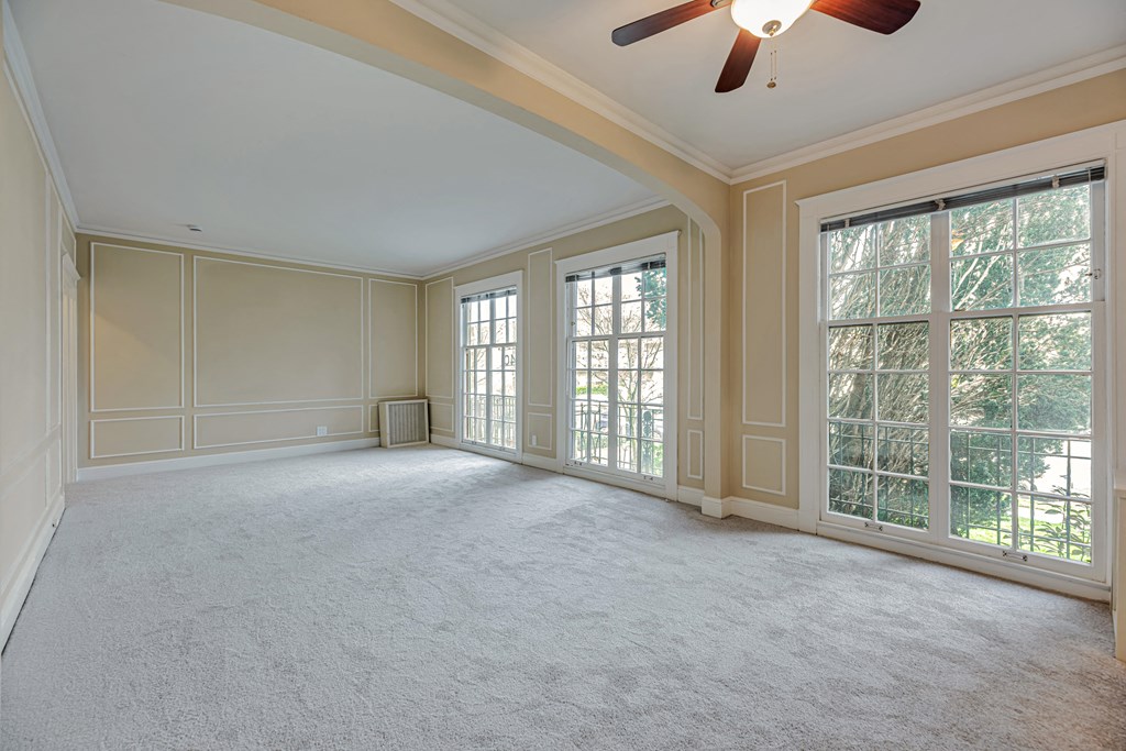 A spacious room with a ceiling fan and large windows.