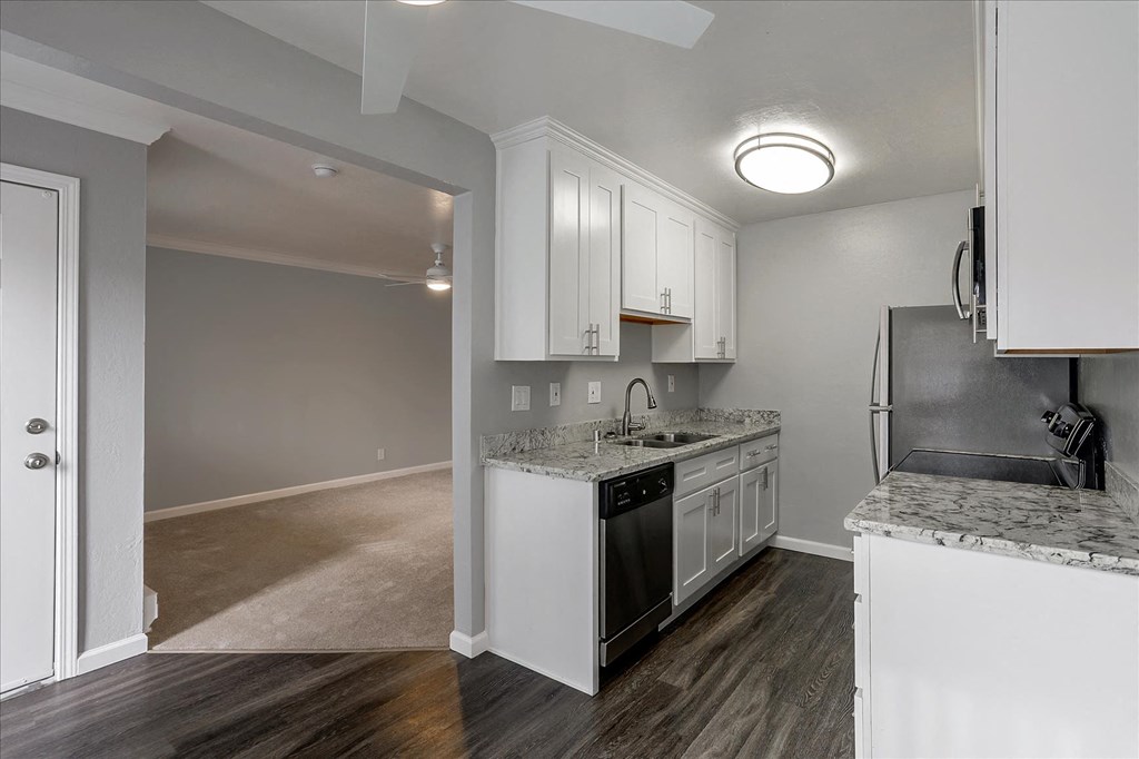A kitchen with white cabinets and a marble countertop.