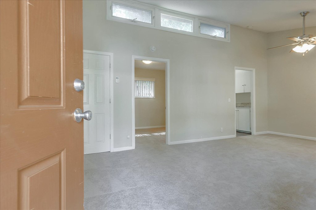 an empty living room with a door open to a kitchen