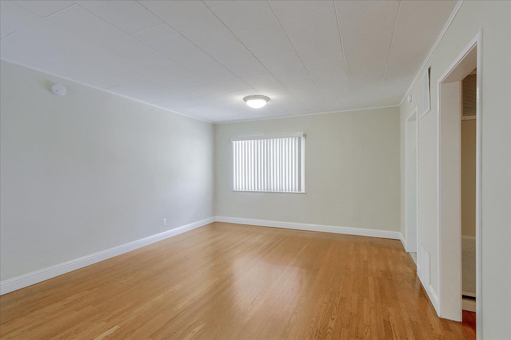 an empty living room with wood floors and a window