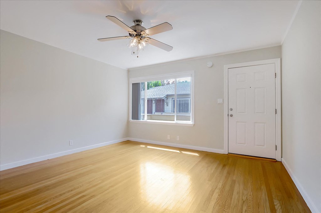 A room with a ceiling fan and wooden flooring.