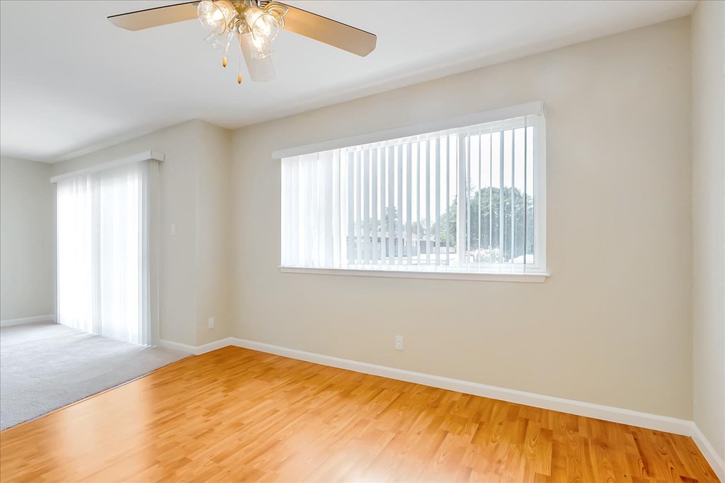 an empty living room with a large window and wooden floors
