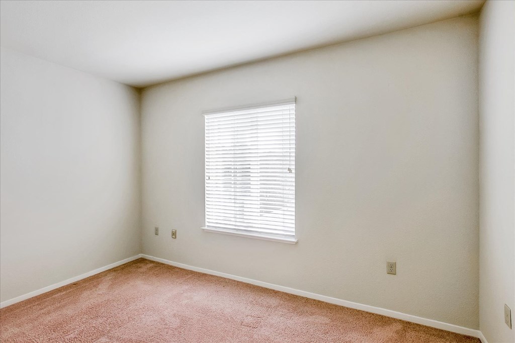 A room with a window covered by white blinds.