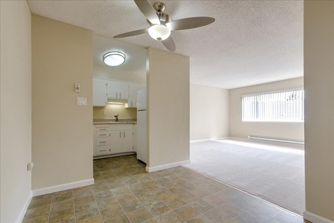 an empty living room and kitchen with a ceiling fan