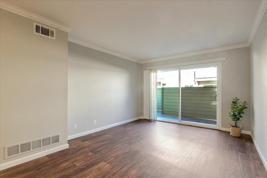 an empty living room with a sliding glass door to a patio