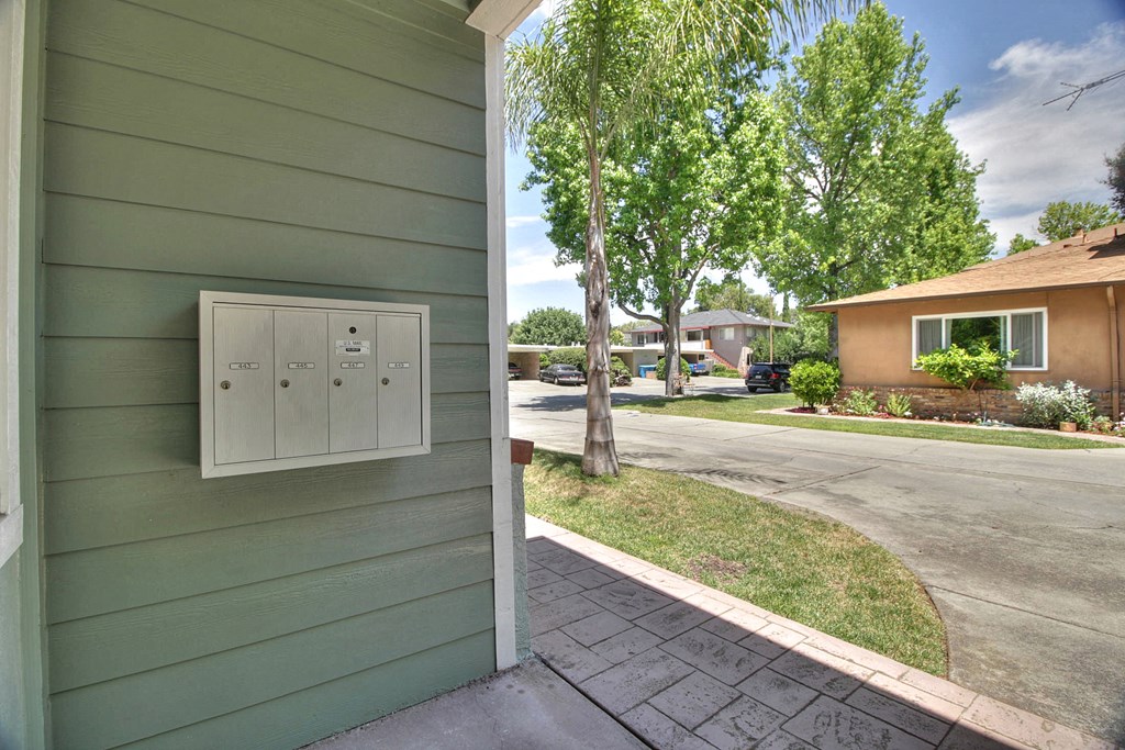 a side view of a green house with a street and trees