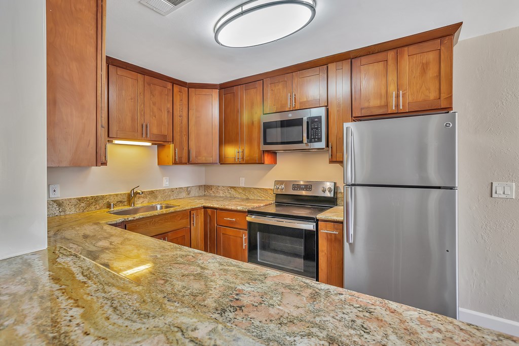 A kitchen with a granite counter top and stainless steel appliances.