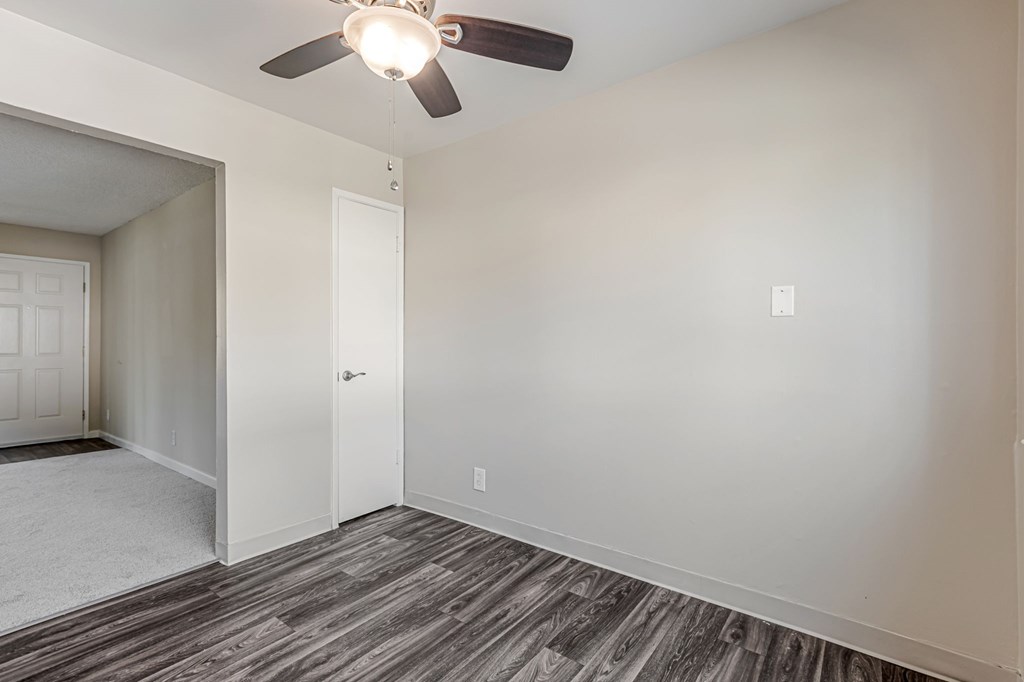 A room with a ceiling fan and wood flooring.