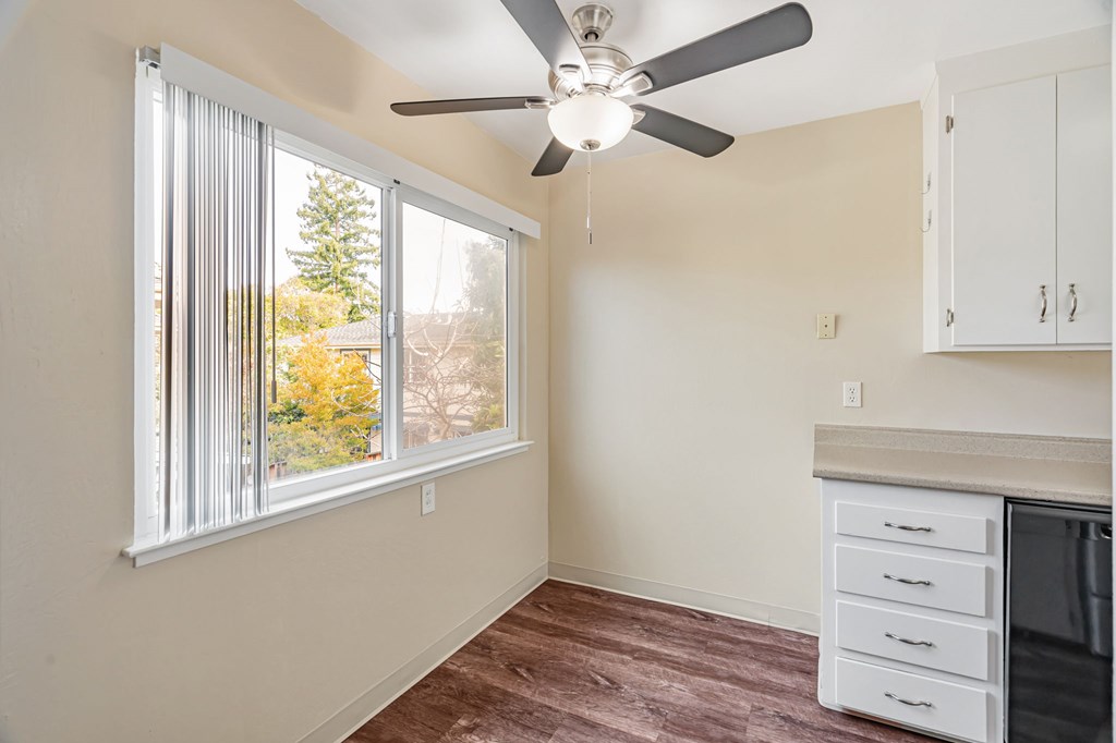 A room with a ceiling fan and a window with blinds.