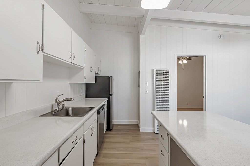 A kitchen with white cabinets and a black refrigerator.