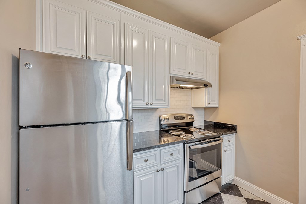 A kitchen with a stainless steel refrigerator, oven, and range hood.