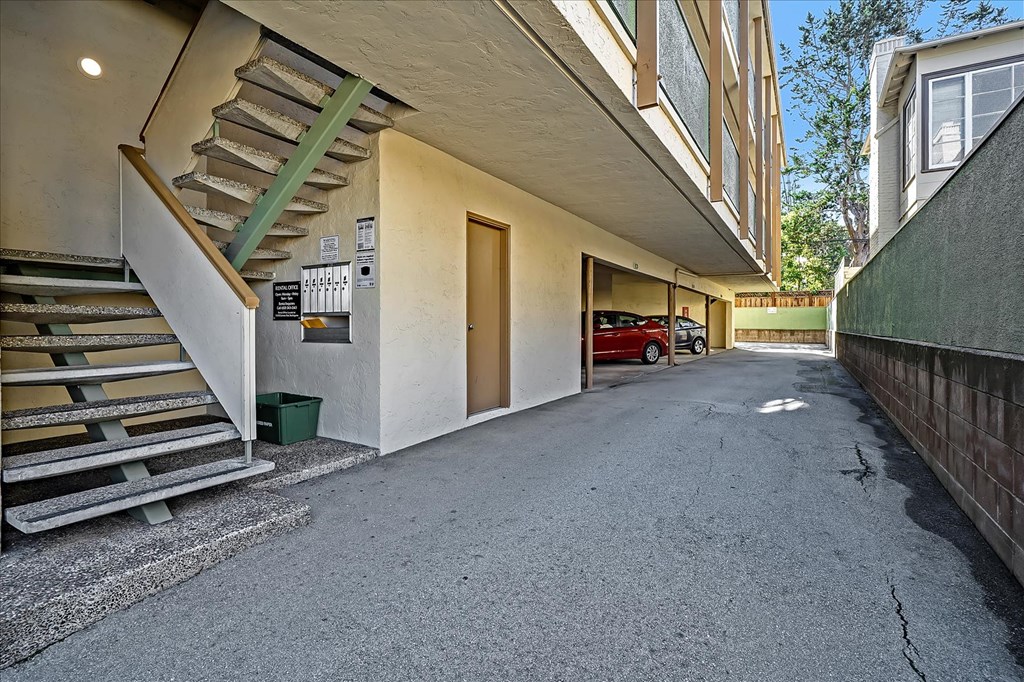 the entrance to an apartment building with stairs and a car parked