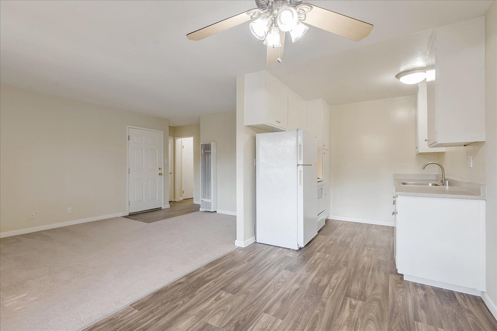 an empty living room and kitchen with a ceiling fan