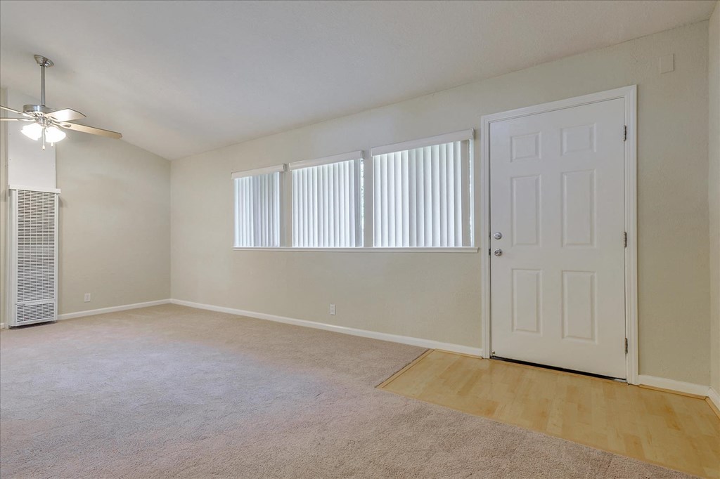 an empty living room with a white door and window