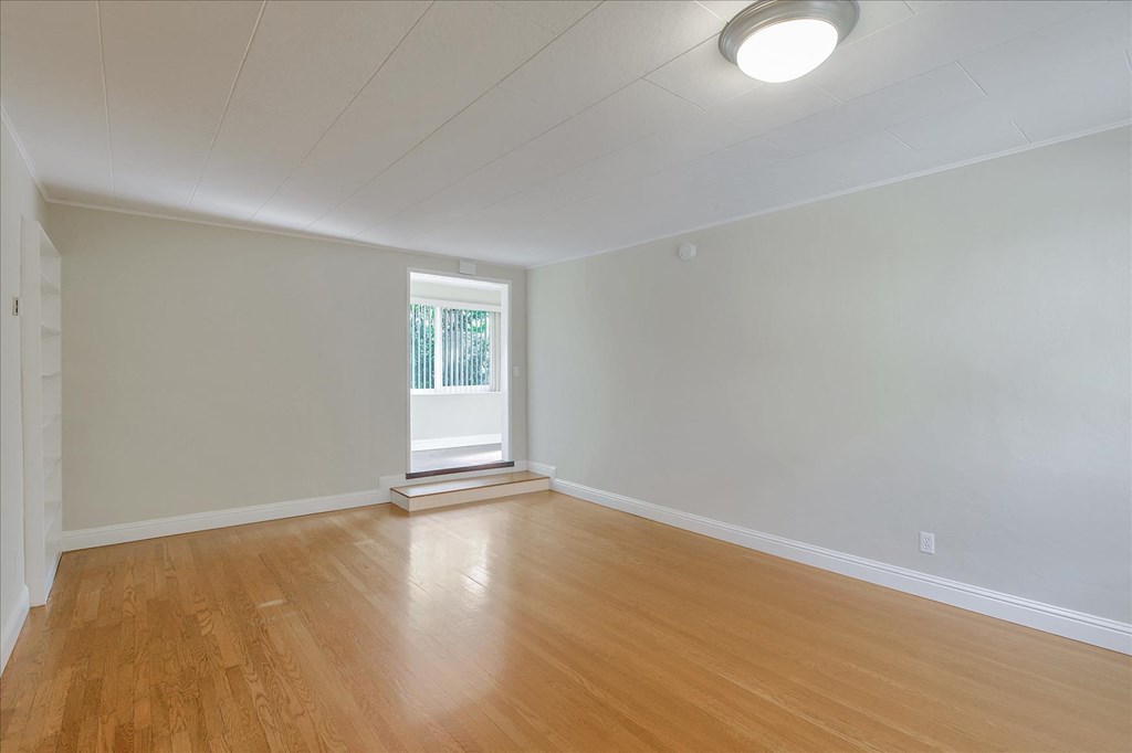an empty living room with wood floors and a window