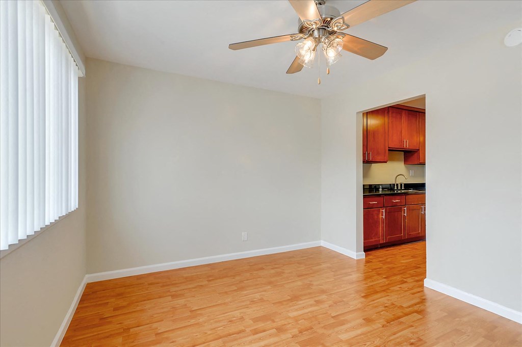 an empty living room with wood floors and a ceiling fan