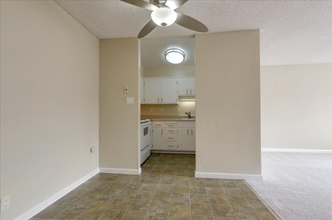 an empty living room and kitchen with a ceiling fan