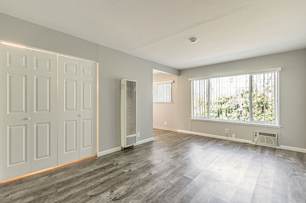 A room with a grey floor and a window with blinds.