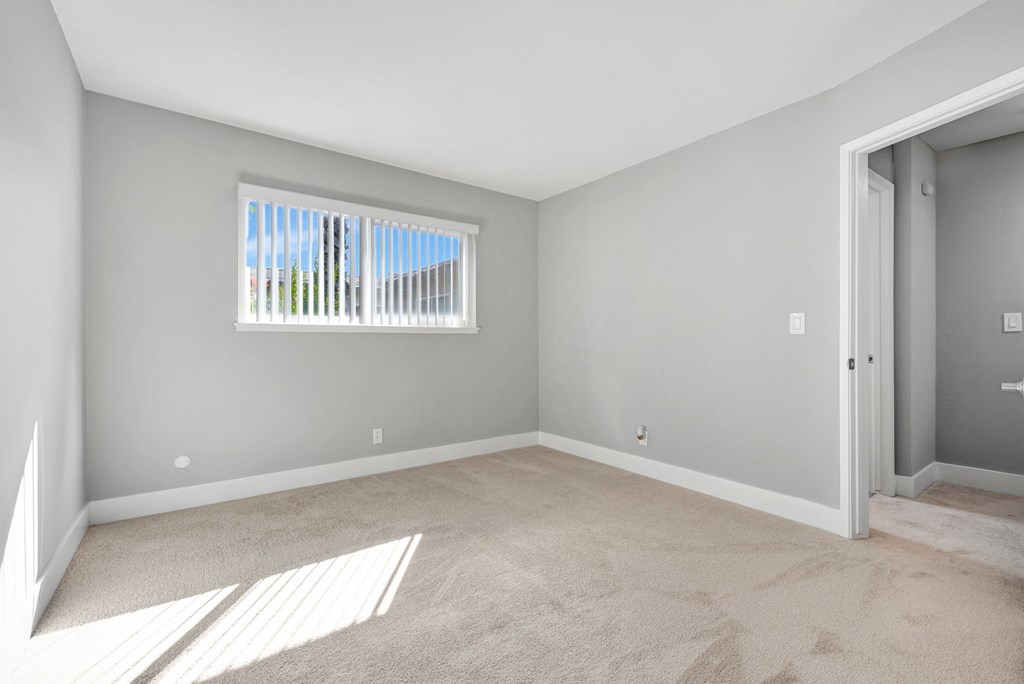 A room with a window and carpeted floor.