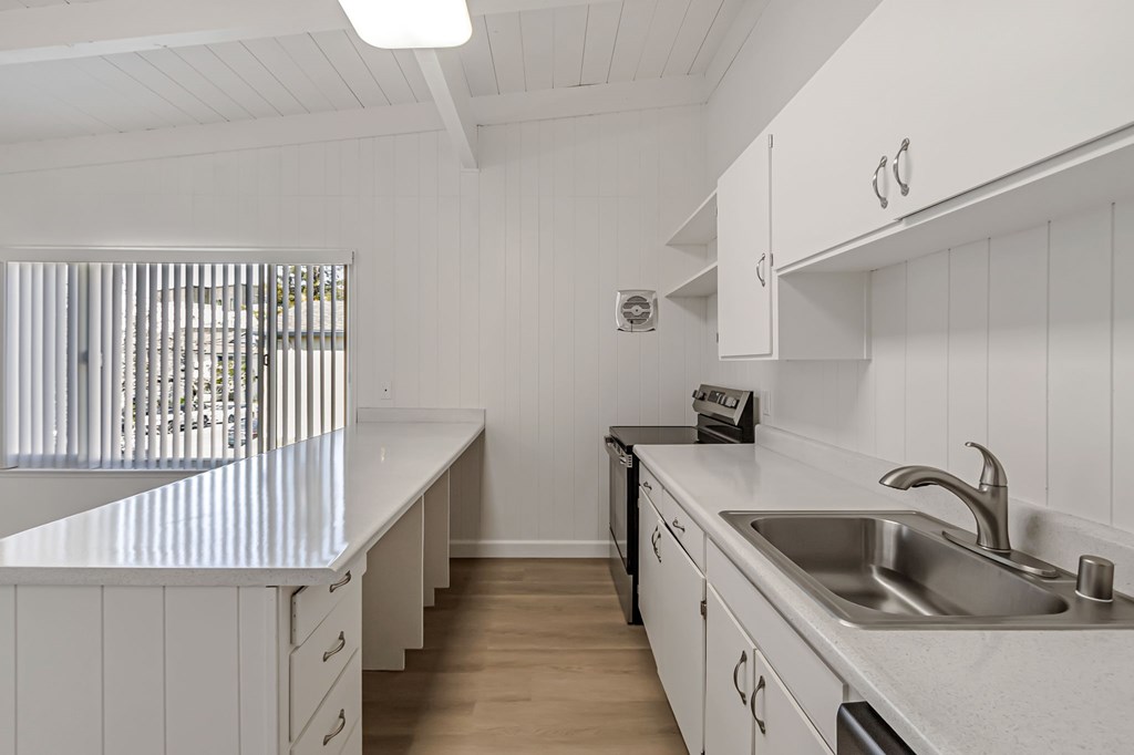 A white kitchen with a sink and a window.