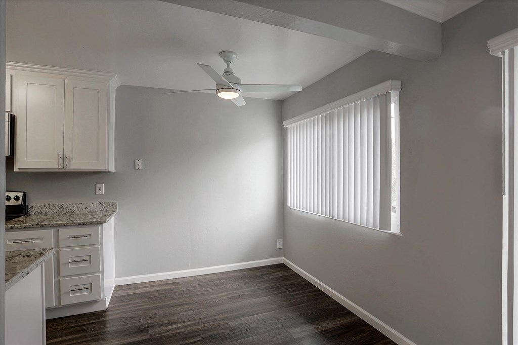 A kitchen with white cabinets and a marble countertop.