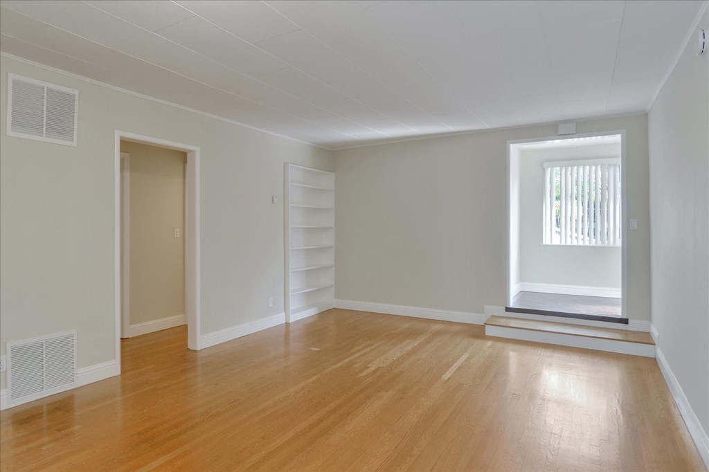 an empty living room with wood floors and a window