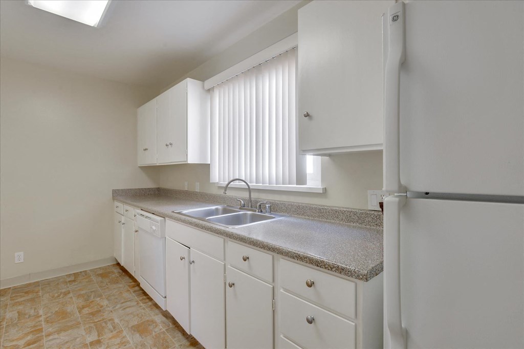 a kitchen with white cabinets and a sink and a refrigerator