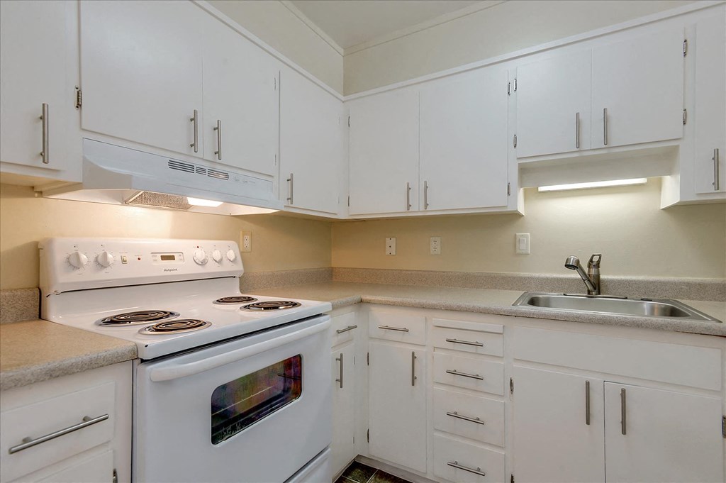 a kitchen with white cabinets and a stove and a sink