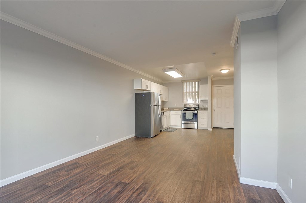 a renovated living room and kitchen with wood flooring and white walls