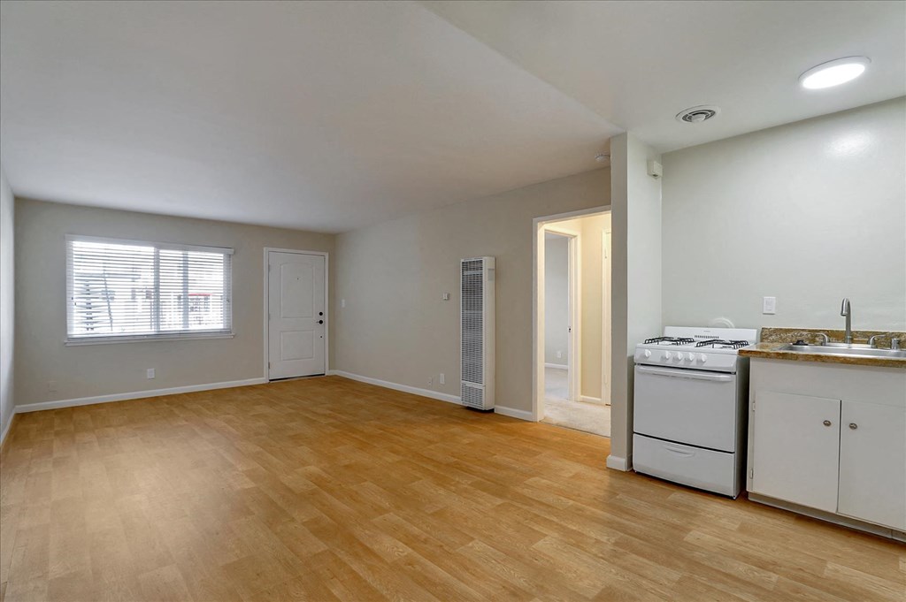 an empty kitchen and living room with a stove and a sink