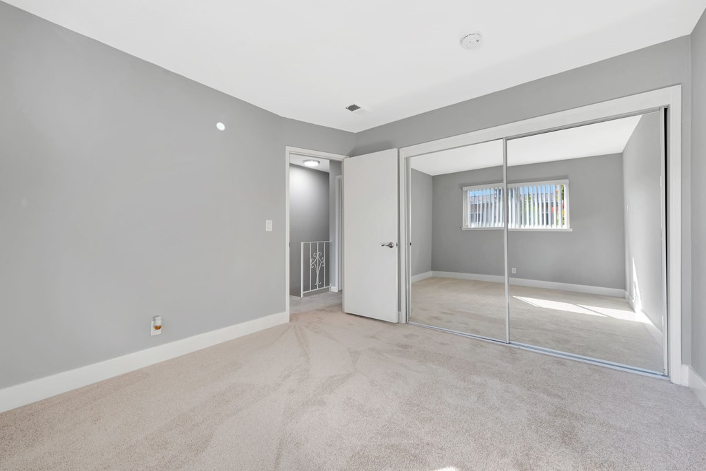 A room with a carpeted floor and a sliding glass door leading to a balcony.