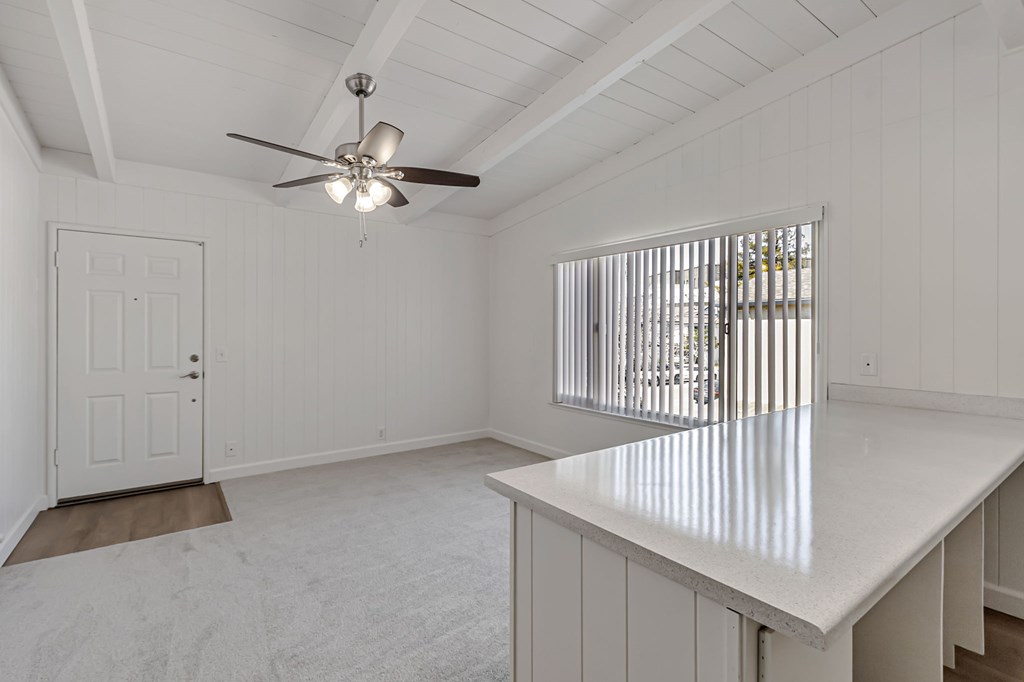 A white room with a ceiling fan and a window with bars.