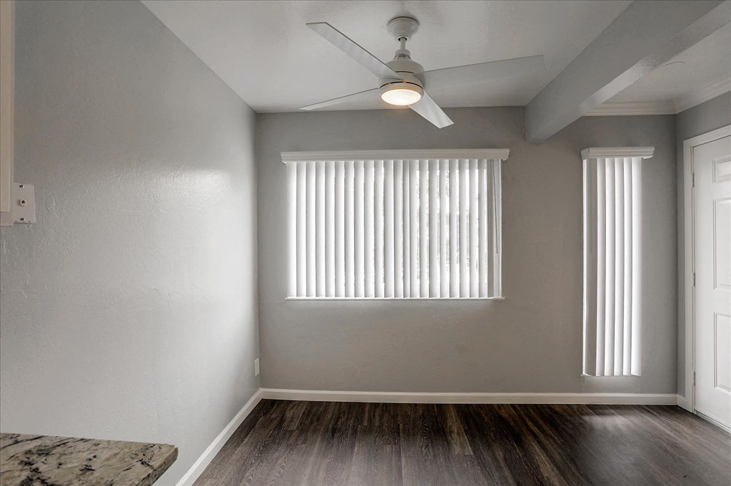 A room with a ceiling fan and a window with blinds.