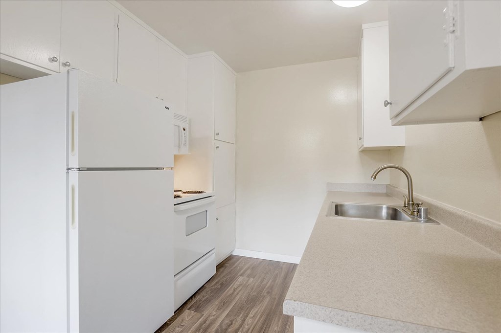 a white kitchen with a sink and a refrigerator